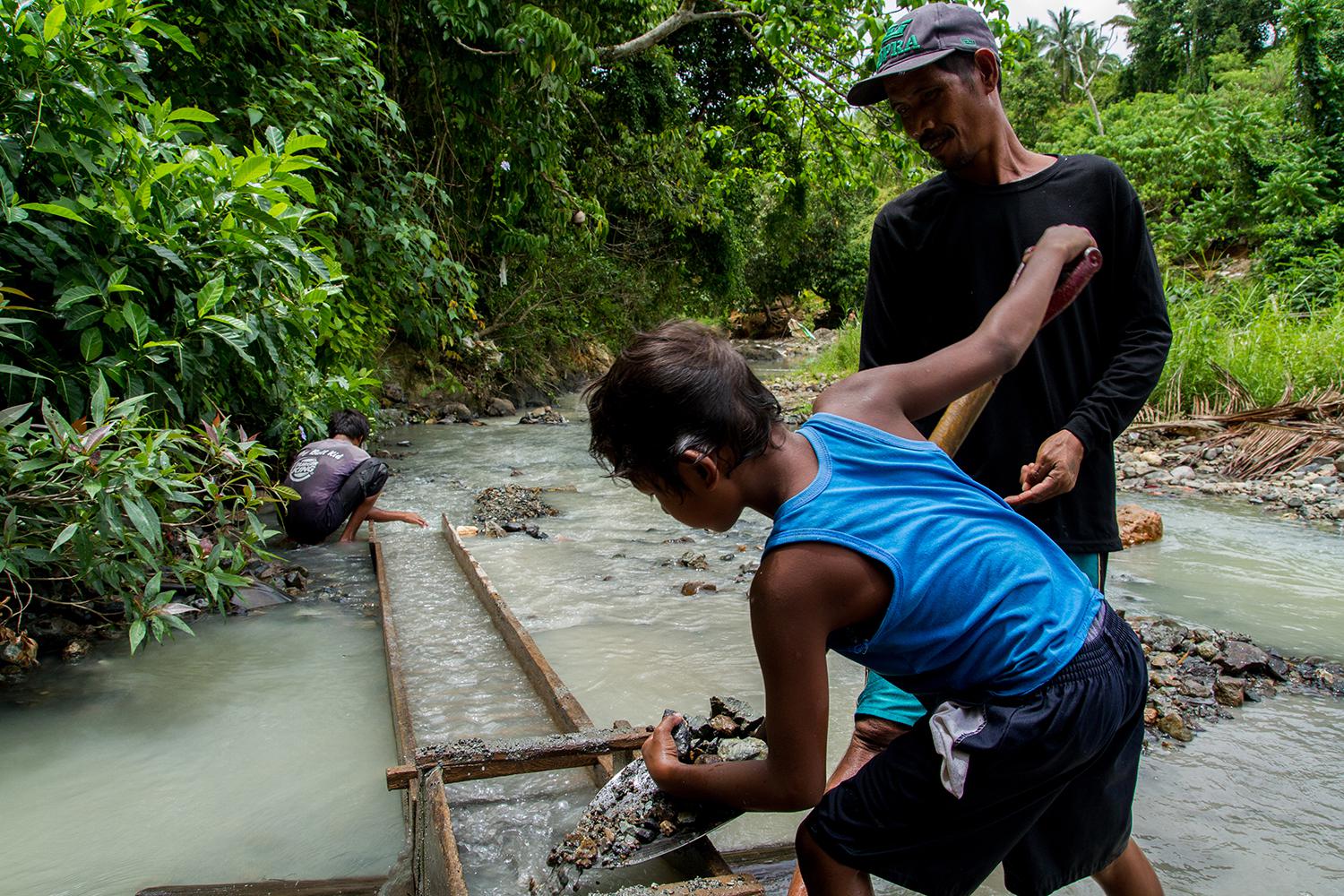 A boy and his father shovel ore from the Bosigon River in Malaya, Camarines Norte.  © 2015 Mark Z. Saludes for Human Rights Watch