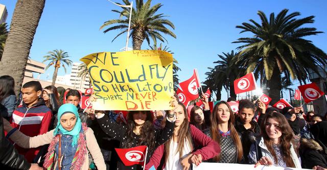 Tunisian students hold flags and placards during a march in memory of 12 presidential guards who were killed in an attack in Tunis.