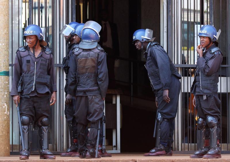 Riot police stand guard as opposition party supporters, arrested following Friday's protest march, arrive at court in Harare, Zimbabwe