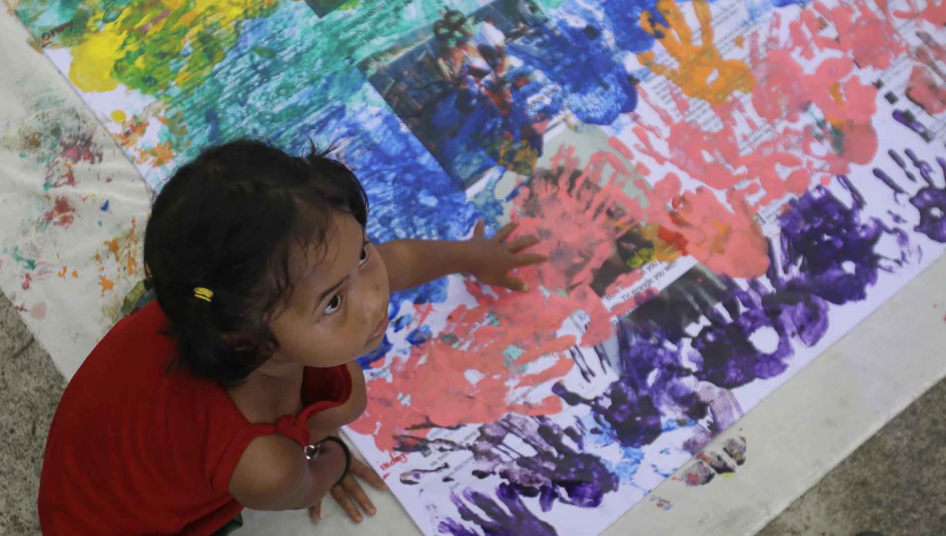 A girl covers anti-LGBT messages in rainbow handprints during a Pride rally in Manila on June 27, 2015.