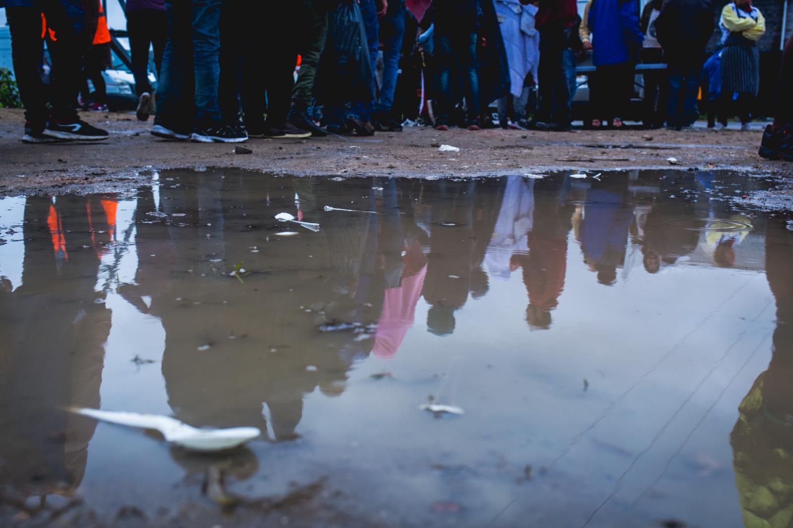 Migrants in Calais gather in the rain for a clothing distribution in an industrial zone on the outskirts of Calais, France. © Futuro Berg/Help Refugees, October 2017