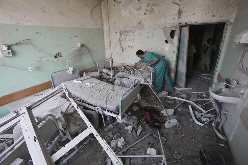 A Palestinian medic inspects a damaged room at Al-Aqsa Martyrs hospital, in Deir el-Balah, central Gaza Strip, after the building was shelled by the Israeli army on July 21, 2014, killing at least 3 people and wounding about 40 others.