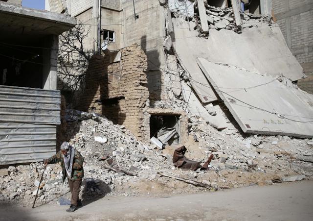 An elderly man walks near a damaged building in the besieged town of Douma in Eastern Ghouta, Syria.