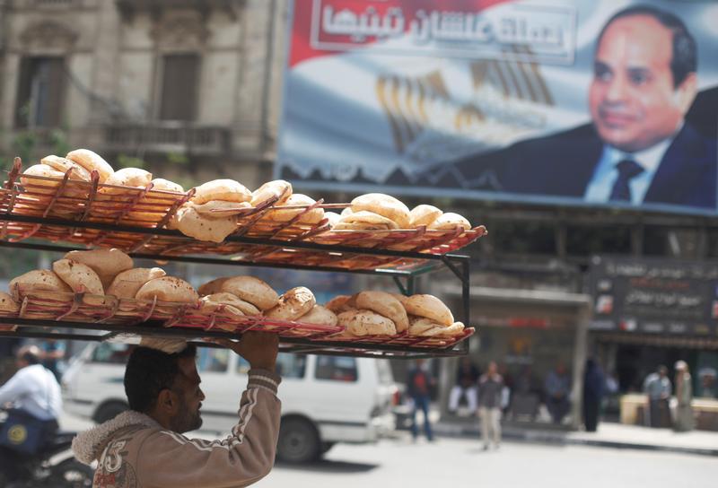 A man carries breads on his head along a busy street near a banner for Egypt's President Abdel Fattah al-Sisi from the campaign titled “Alashan Tabneeha” (So You Can Build It) after election results in Cairo, Egypt, April 3, 2018. REUTERS/Amr Abdallah Dal