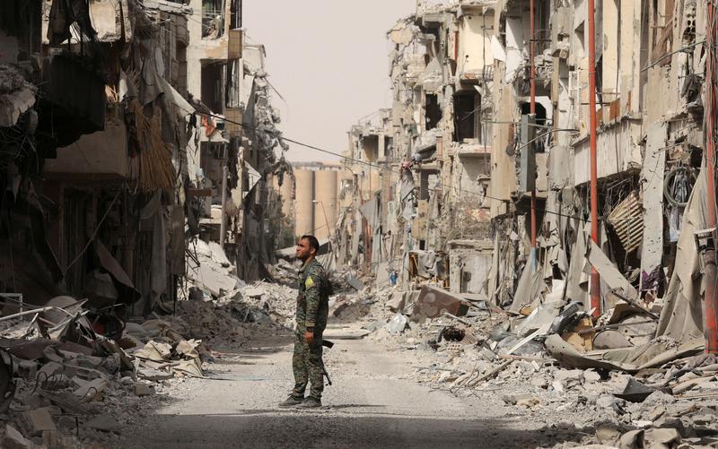 A fighter from Syrian Democratic Forces (SDF) stands next to debris of damaged buildings in Raqqa, Syria, September 25, 2017. © 2017 REUTERS