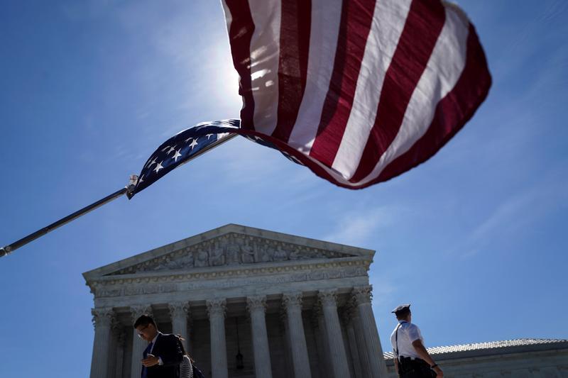 A man holds a flag outside the U.S. Supreme Court, as the Trump v. Hawaii case regarding travel restrictions in the U.S. remained pending, in Washington, U.S., June 25, 2018.