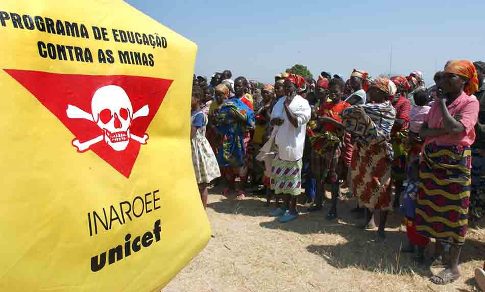 Villagers stand in front of a Unicef banner warning of landmines outside Caala, Angola