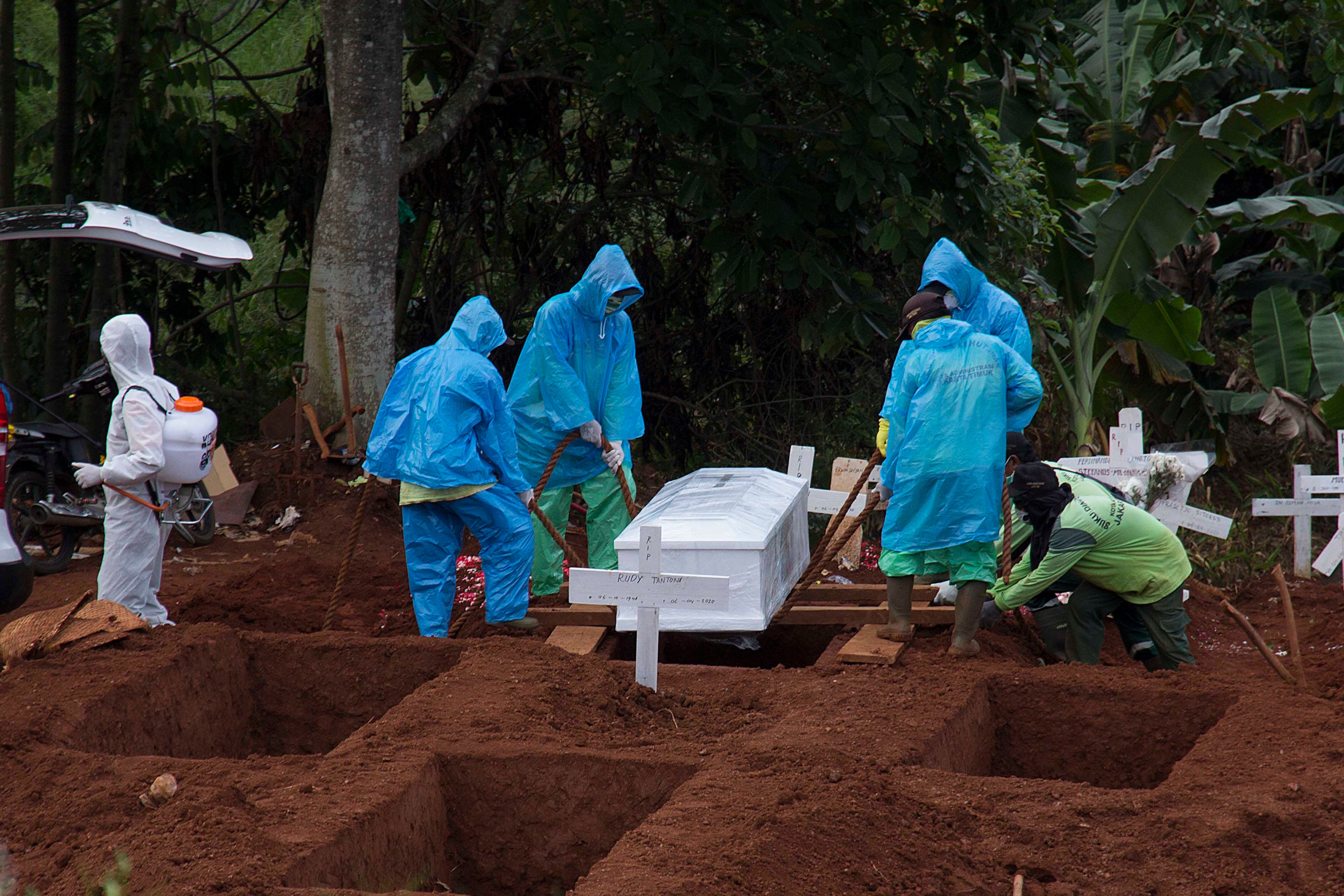 Cemetery workers burying a victim from the COVID-19 coronavirus outbreak, during a funeral in Jakarta, Indonesia, April 7, 2020. 