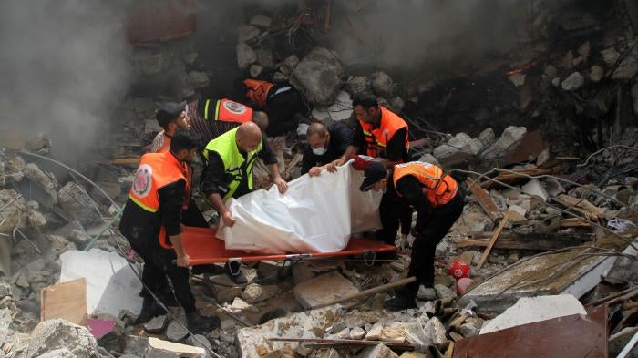 Members of the Palestinian civil defense remove the body of one of the 44 civilians killed after three multi-story residential buildings collapsed as a result of Israeli airstrikes in central Gaza City