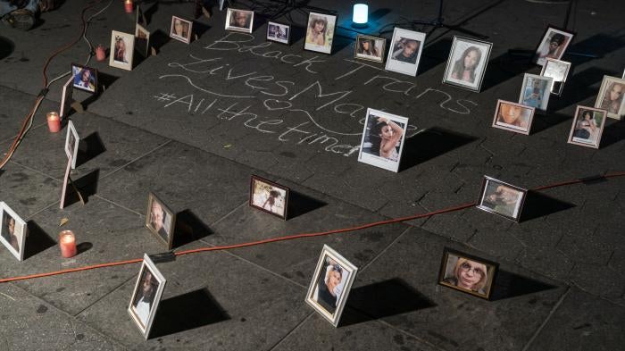 Framed photos placed on the ground around chalk writing that says "Black trans lives matter #allthetime"