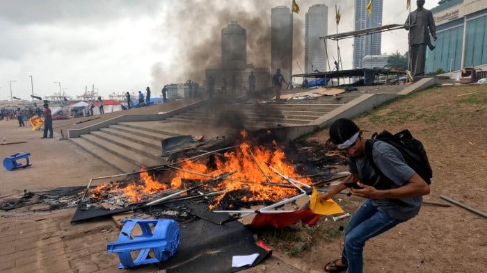 A Sri Lankan anti-government protester tries to save some papers from a tent that was set on fire