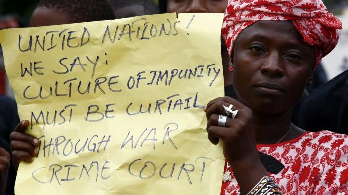 A woman holds a placard during a peaceful demonstration in the Liberian capital Monrovia, July 4, 2006, calling on the visiting U.N. Secretary General Kofi Annan to establish a war Crimes court in Liberia as a means to bring justice to the country. 