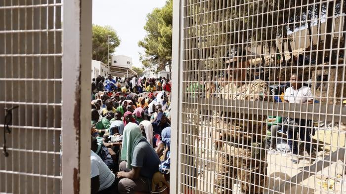 People sit on the ground of the overcrowded migrant reception center on Lampedusa, an Italian island in the Mediterranean Sea, on September 16, 2023.