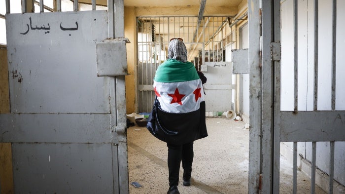 A woman wearing a Syrian opposition flag visits Sednaya prison near Damascus, Syria, December 12, 2024