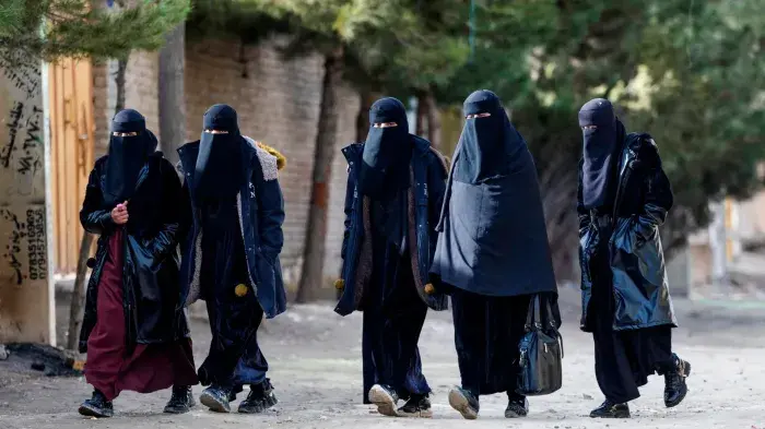 Afghan niqab-clad women walk along a street on the outskirts of Kabul.
