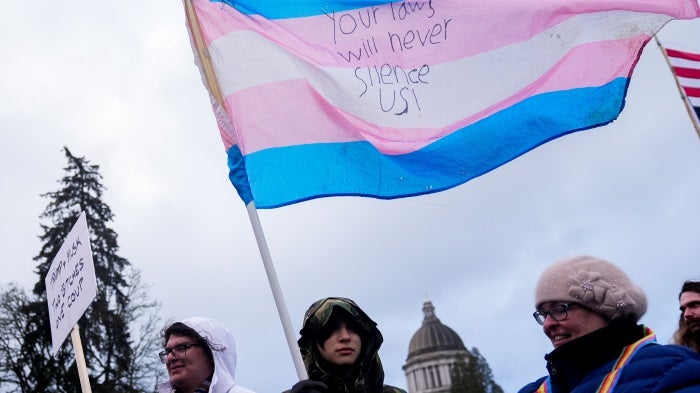 Liv Y., center, holds a transgender pride flag as people gather to protest against the Trump administration near the Washington State Capitol building, in Olympia, Washington, February 5, 2025.