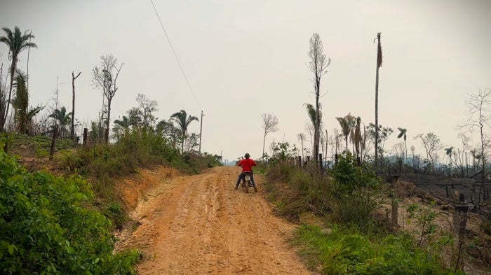 A man rides a motorcycle down a dirt road