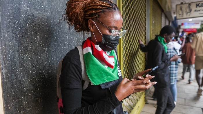 A protestor checks her phone during the youth-led protests against proposed tax hikes in Kenya's finance bill 2024/2025.
