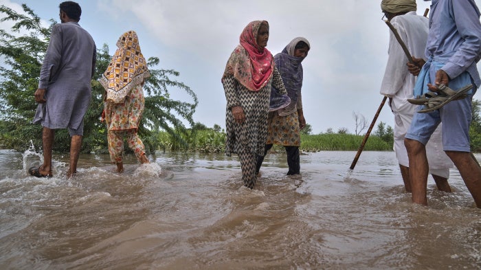 Villagers wade through a flooded area.
