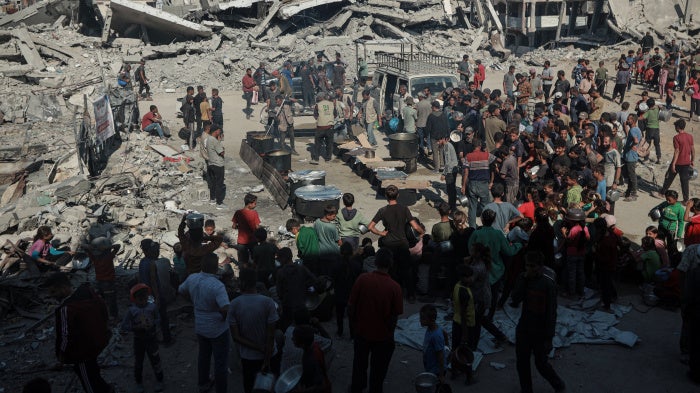 Palestinians flock to the area where a charitable organization distributes hot food as food crisis persists in Beit Lahia, Gaza on October 28, 2025. 