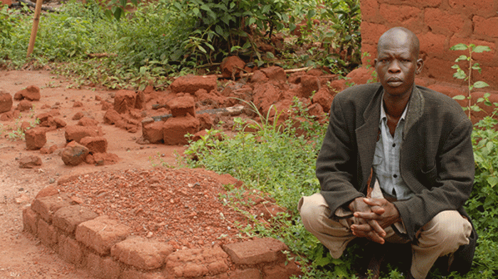 Jean Baptiste Nguondija, a resident of Ngbada, Central African Republic, by the grave of his 10 year-old daughter Nathana Poura. Nguondija has lost 5 children since the conflict began in 2013. 