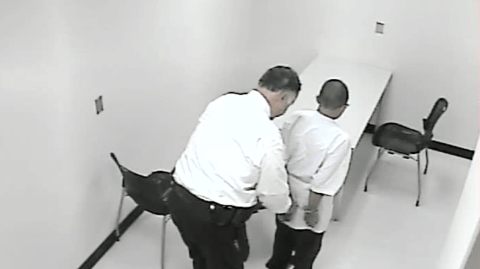 A still from a police interrogation video shows a 13-year-old boy being handcuffed. The pressure of the interrogation caused him to confess to a murder he did not commit. 