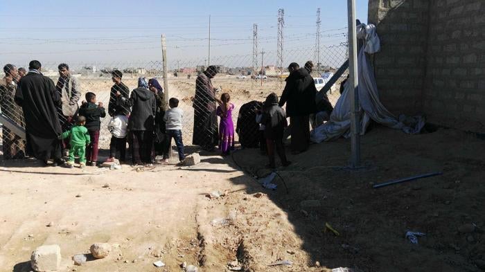 Residents of Shahama camp speak with relatives through the camp fence. 