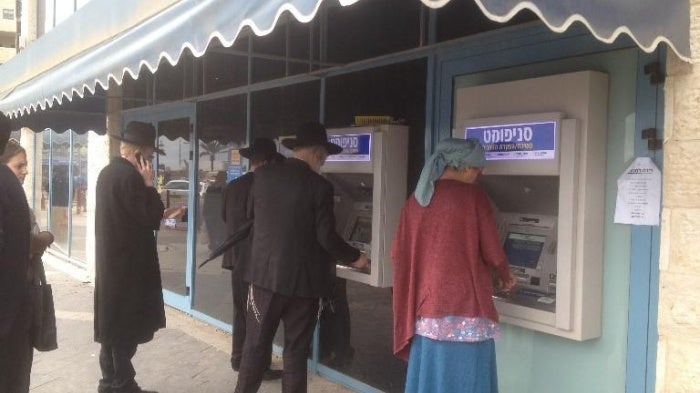Customers use ATMs outside a bank branch in the Israeli settlement of Modi'in Ilit.