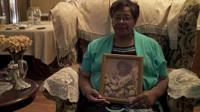Ms. Frances Ford, executive director of Sowing Seeds of Hope, in her home in August 2018, holding a picture of her mother, who died from cervical cancer after being diagnosed in 1980. 