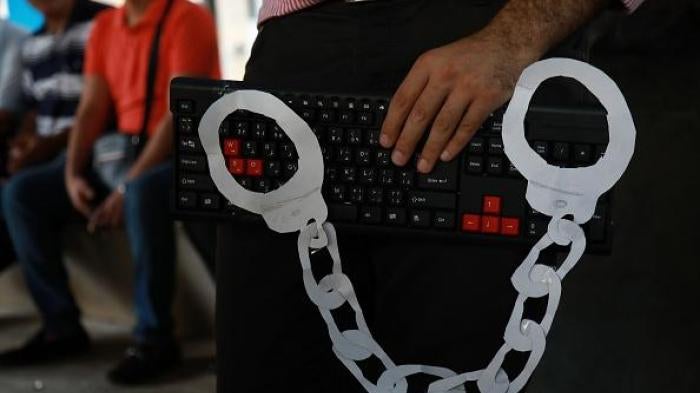 An activist holds a computer keyboard and makeshift handcuffs in downtown Beirut on July 24, 2018, during a protest against the recent wave of interrogations by Lebanese security forces of people making political comments online. 