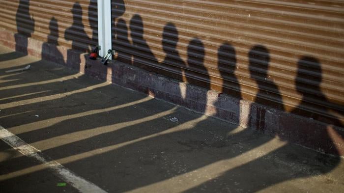 Shadows of people detained by Russian police, suspected of violating immigration rules during an action seen on containers at a street market in Moscow, Russia, August 7, 2013. © AP Photo/Alexander Zemlianichenko