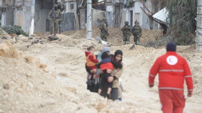 Women carry children as Israeli forces forcibly displace them from Nur Shams refugee camp 