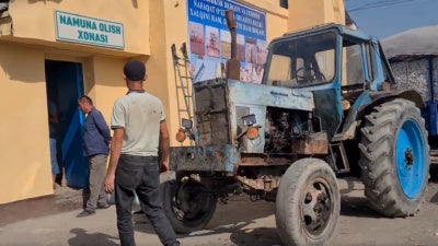 Deux agriculteurs ouzbeks près d’un tracteur transportant du coton récolté s’apprêtaient à entrer dans la salle d'échantillonnage d'une usine d'égrenage de coton dans la région de Ferghana, en Ouzbékistan, en septembre 2023. 