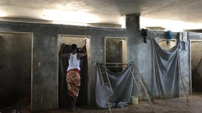 A detainee stands outside a toilet stall in the Ain Zara detention center, Tripoli, July 5, 2018. 