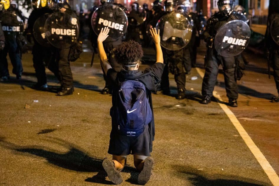 A demonstrator kneels facing a police line in front of the White House while protesting the police killing of George Floyd. Washington, DC, May 31, 2020. 