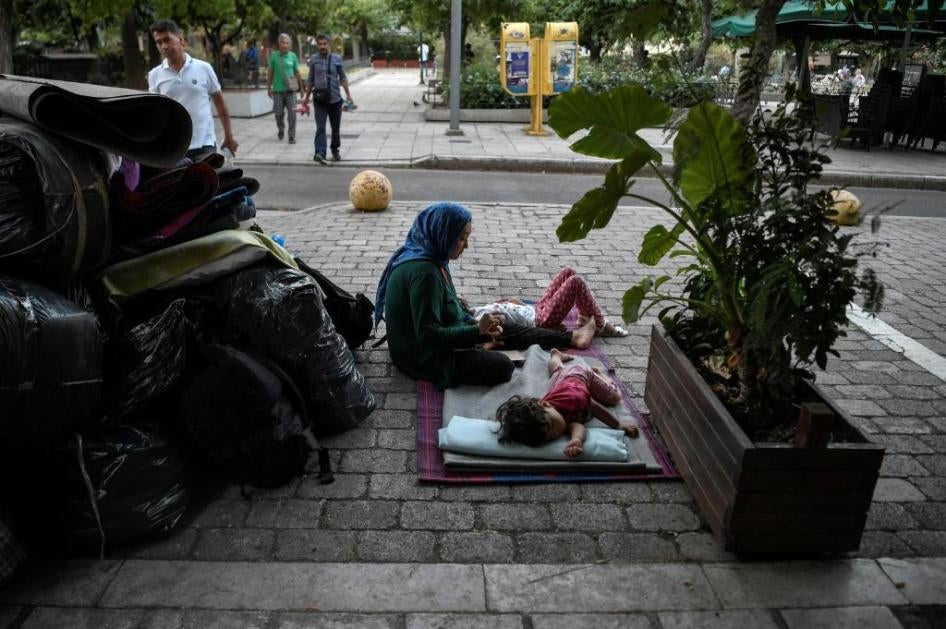 A woman sits with her children in Victoria Square in Athens, Greece, awaiting transfer after being evicted from their place of residence, July 20, 2020.