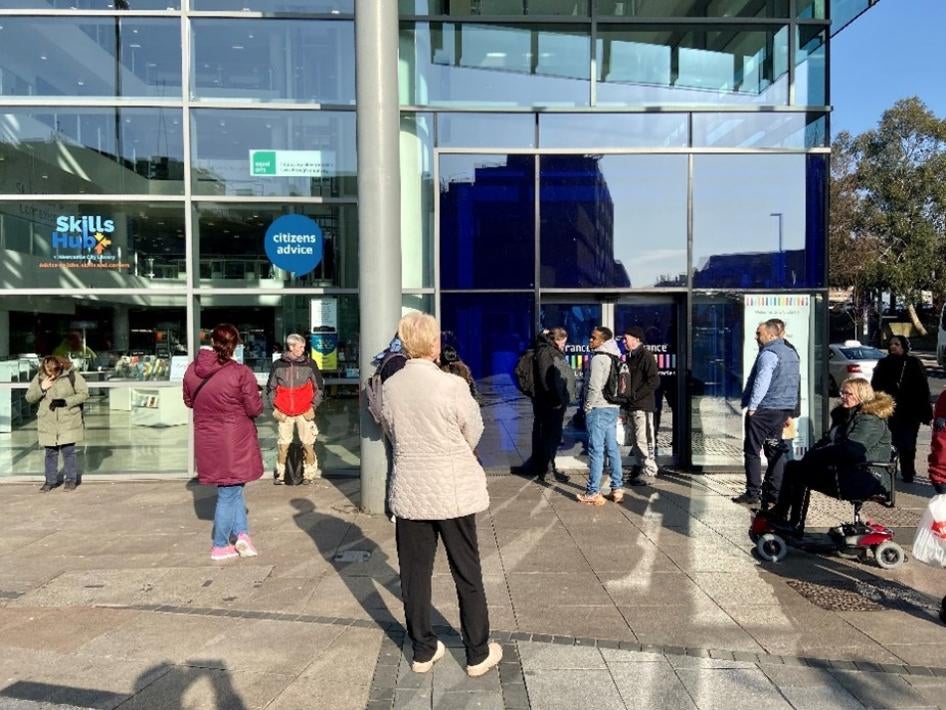 People in a line outside of a modern library building