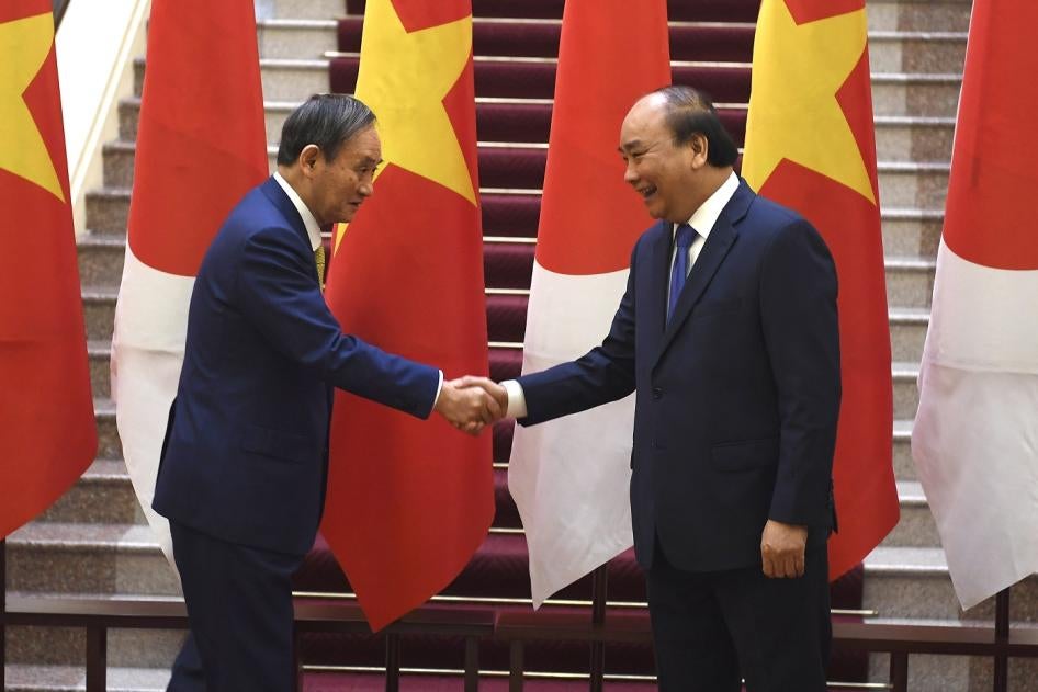 Japan's Prime Minister Yoshihide Suga, left, shakes hands with Vietnam's Prime Minister Nguyen Xuan Phuc after the exchange of documents at the Government Office in Hanoi on Monday, October 19, 2020. 