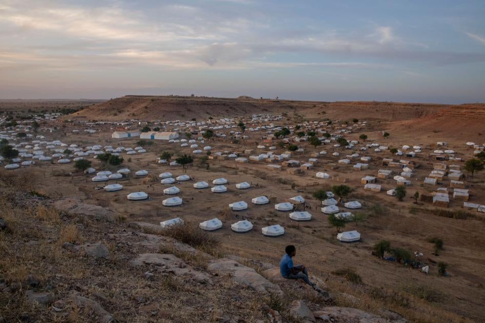 A boy sits atop a hill overlooking part of Um Raquba refugee camp, hosting people who fled the conflict in the Tigray region of Ethiopia, in al-Gadaref state, eastern Sudan, December 14, 2020. 