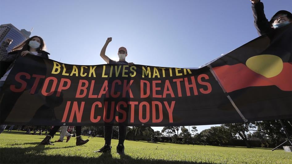 People hold a banner as thousands gather at a Black Lives Matter protest in Sydney.