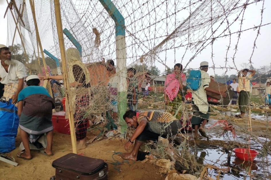 A man climbs through barbed wire fencing at a Rohingya refugee camp in Cox’s Bazar, Bangladesh, as a massive fire swept through the camps on March 22, 2021.