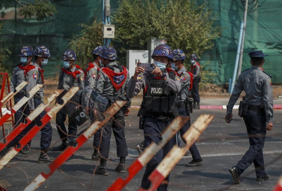 A police officer takes visuals of protesters close to the Indonesian Embassy in Yangon, Myanmar Wednesday, Feb. 24, 2021. 