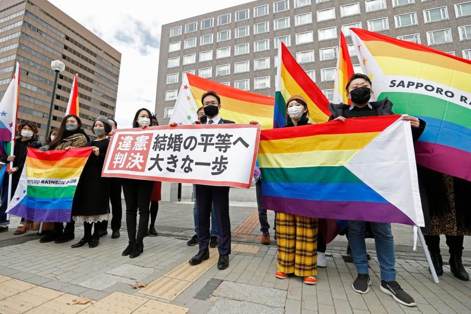 Lawyers and supporters hold rainbow flags and a banner outside Sapporo District Court in Sapporo, Japan, March 17, 2021. 