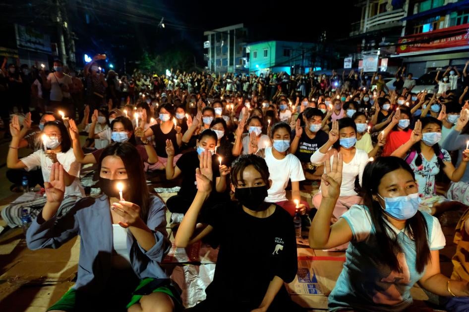 Protesters flash the three-fingered salute and hold candles during a rally at night in Yangon, Myanmar, March 14, 2021.