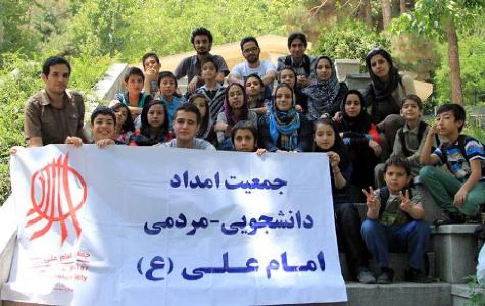 Members of the "Imam Ali Association" hold a banner with the association's logo and name.