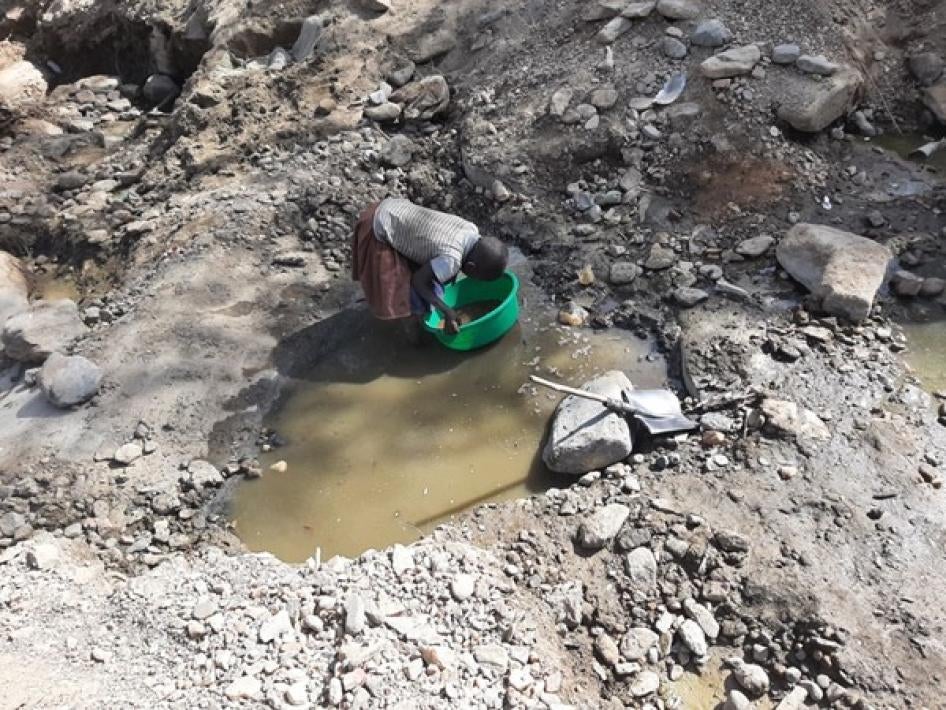 A 9-year old girl collects sand at a mining site in Uganda. 