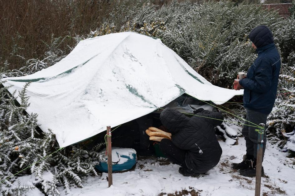 Volunteers distribute food and tea to a group of Afghan boys at a migrant encampment in Calais, northern France, February 2021.