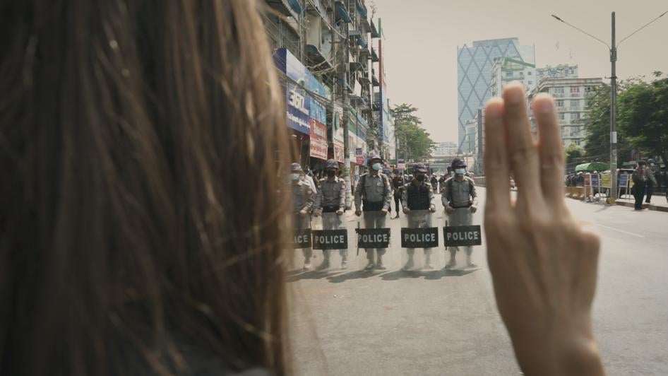 Myanmar Diaries screengrab of protester holding up three-finger salute in front of security forces