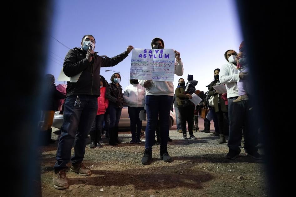 People hold a protest sign that reads "Save asylum" 