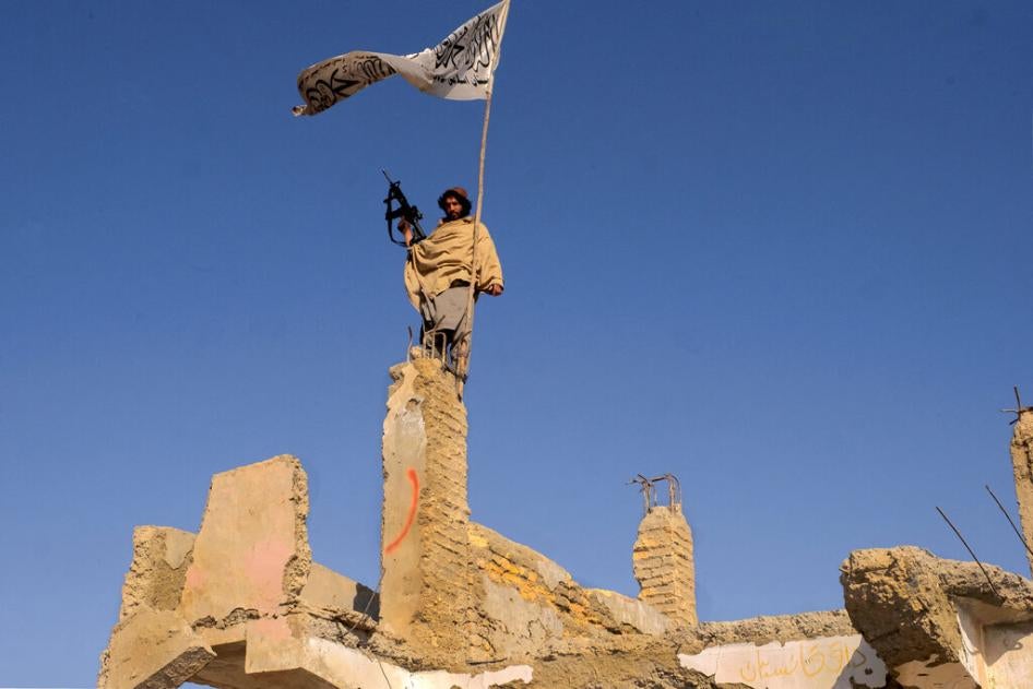 A Taliban fighter raises a flag in the ruins of Sangin, Helmand province, Afghanistan, November 30, 2021.